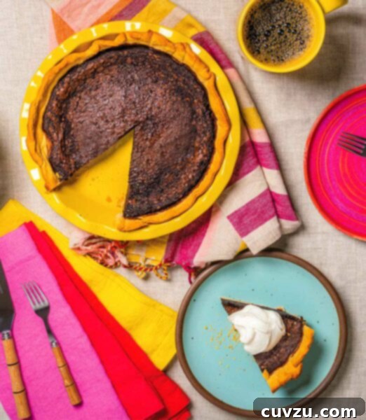 A table with colourful napkins, a plate with a slice of pie , a cup of coffee, and a yellow pie plate with a chocolate buttermilk pie that's missing one slice.