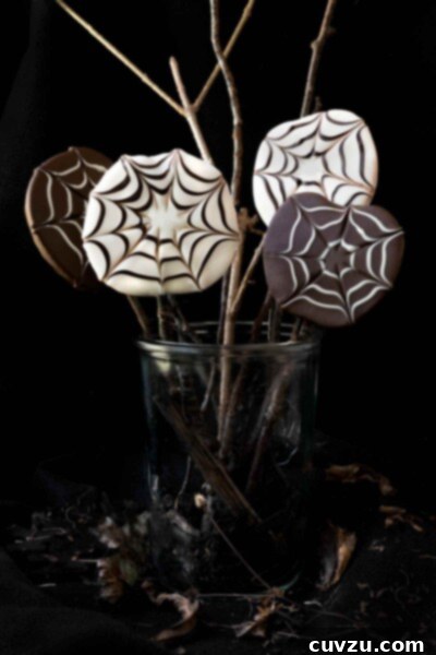 Four chocolate covered apple slices with a spider web design in a jar.