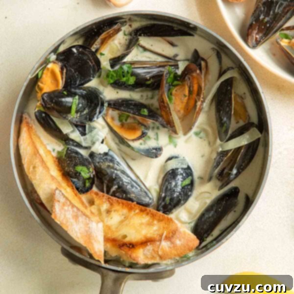 A copper saucepan filled with mussels in a creamy white wine garlic sauce with lemons.