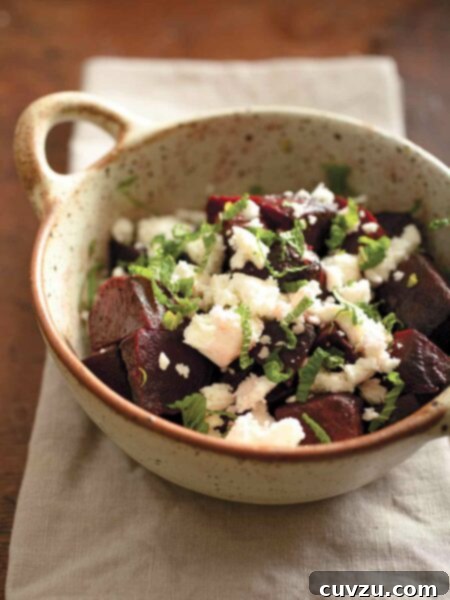 Roasted beet, feta, and mint salad in a pottery bowl on a linen napkin.