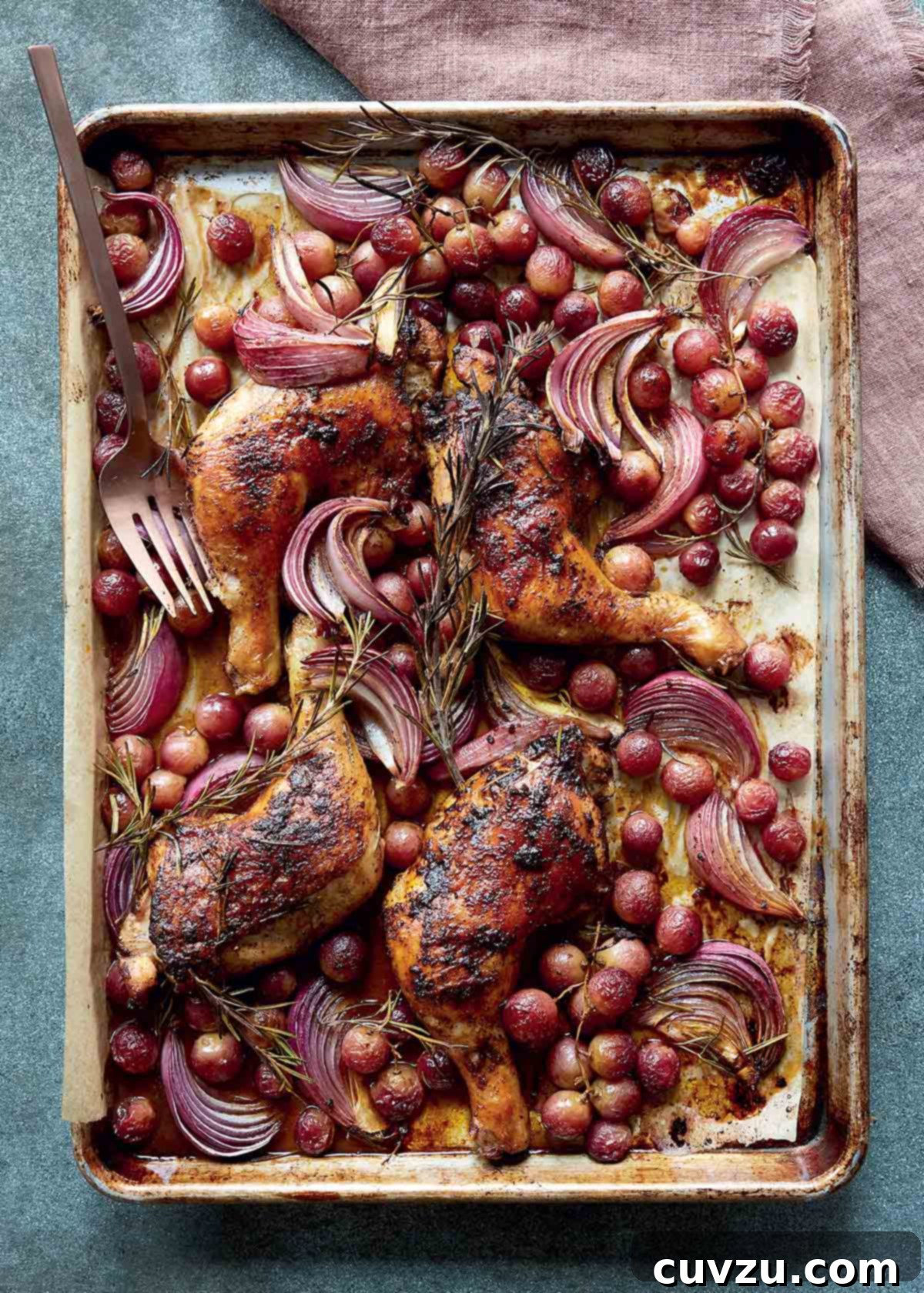 Biberiye Fısıltılı, Üzüm Esintili Fırın Tavuğu 2 Sheet pan chicken with rosemary and grapes on a large metal pan with a fork, on a linen napkin.