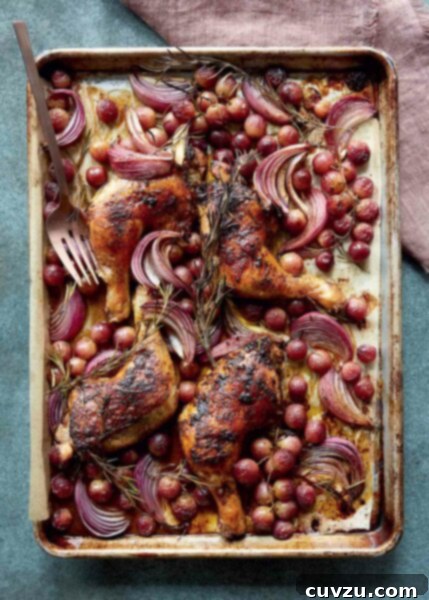 Sheet pan chicken with rosemary and grapes on a large metal pan with a fork, on a linen napkin.
