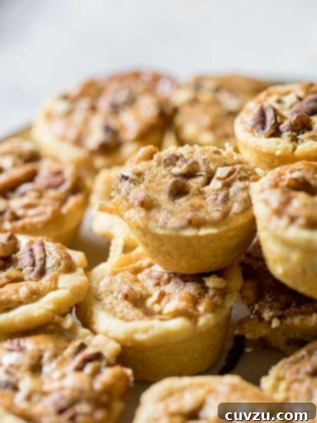 Pecan tassies in close-up, piled on top of each other.
