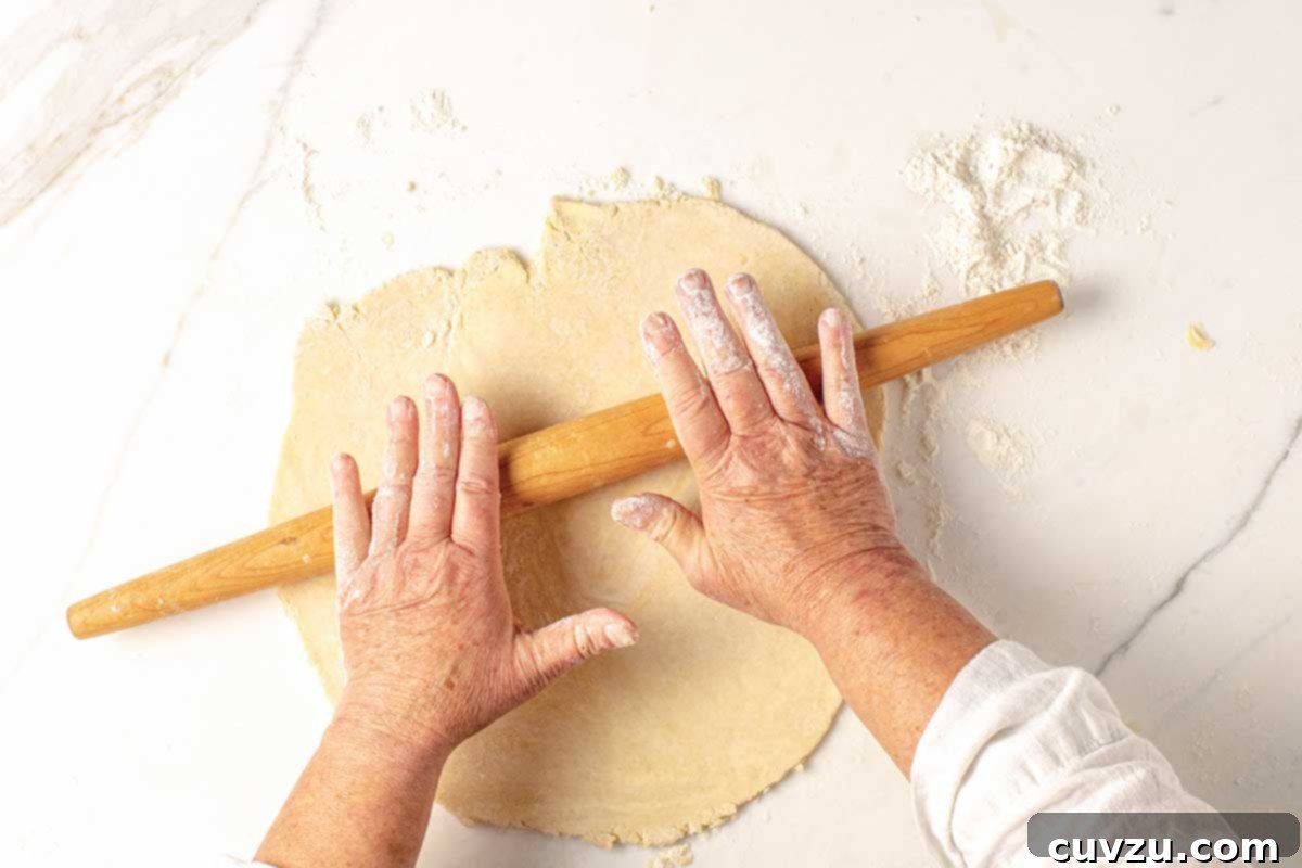 Roll Out a Flawless Pie Crust Every Time 4 A person demonstrating the roll, turn, and repeat method for pie dough, ensuring an evenly shaped crust.