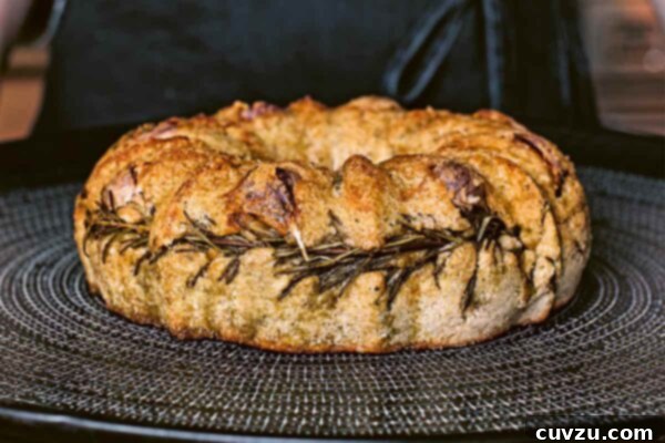 Artisan Rosemary Garlic Sourdough Loaf 4 A loaf of rosemary-garlic sourdough bread on a black and white plate, highlighting its shape and crust.