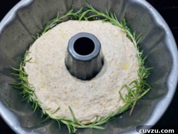 Artisan Rosemary Garlic Sourdough Loaf 6 A Bundt pan with rosemary-garlic sourdough dough shaped like a donut, ready for proofing.