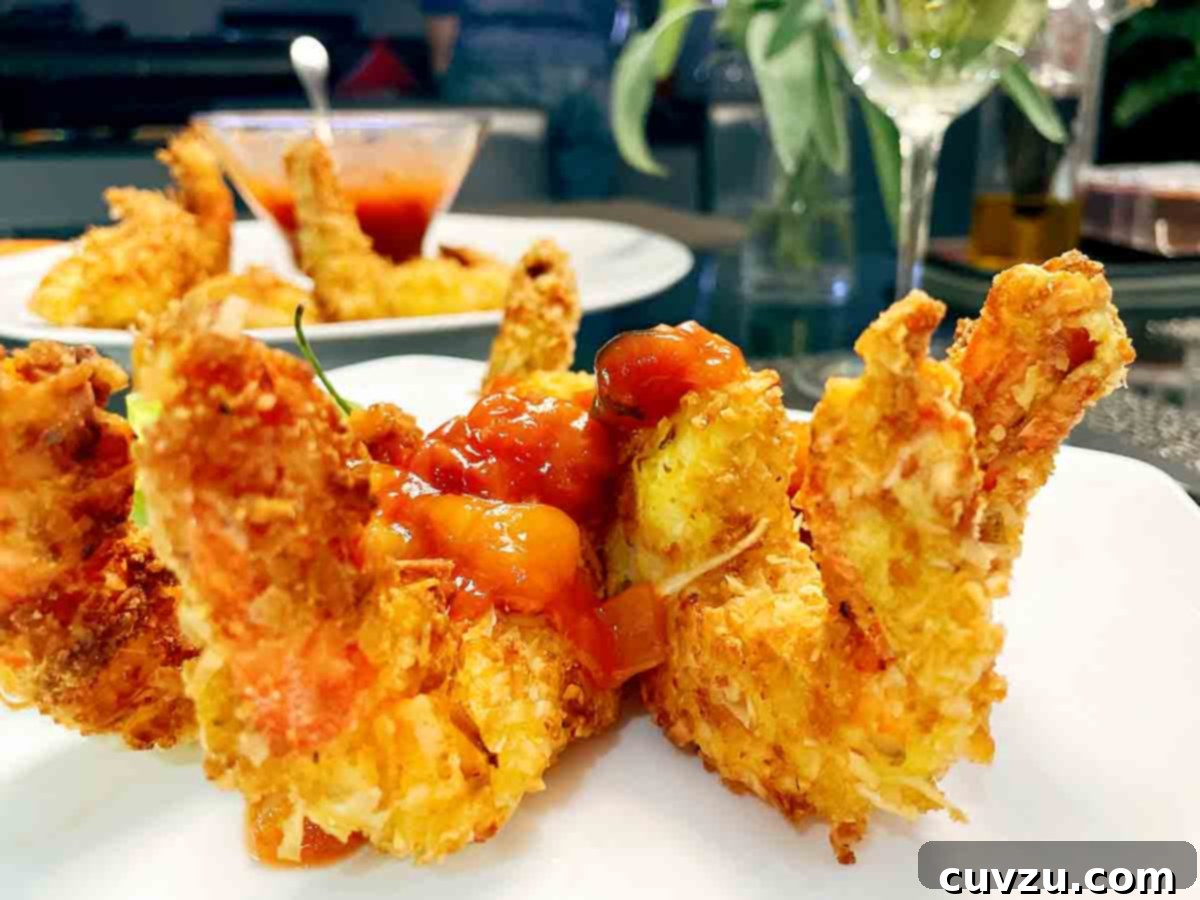 Tropical Coconut Shrimp 5 Coconut shrimp on a white plate with mango salsa, as prepared by Ilda Costa-Sarnicki.