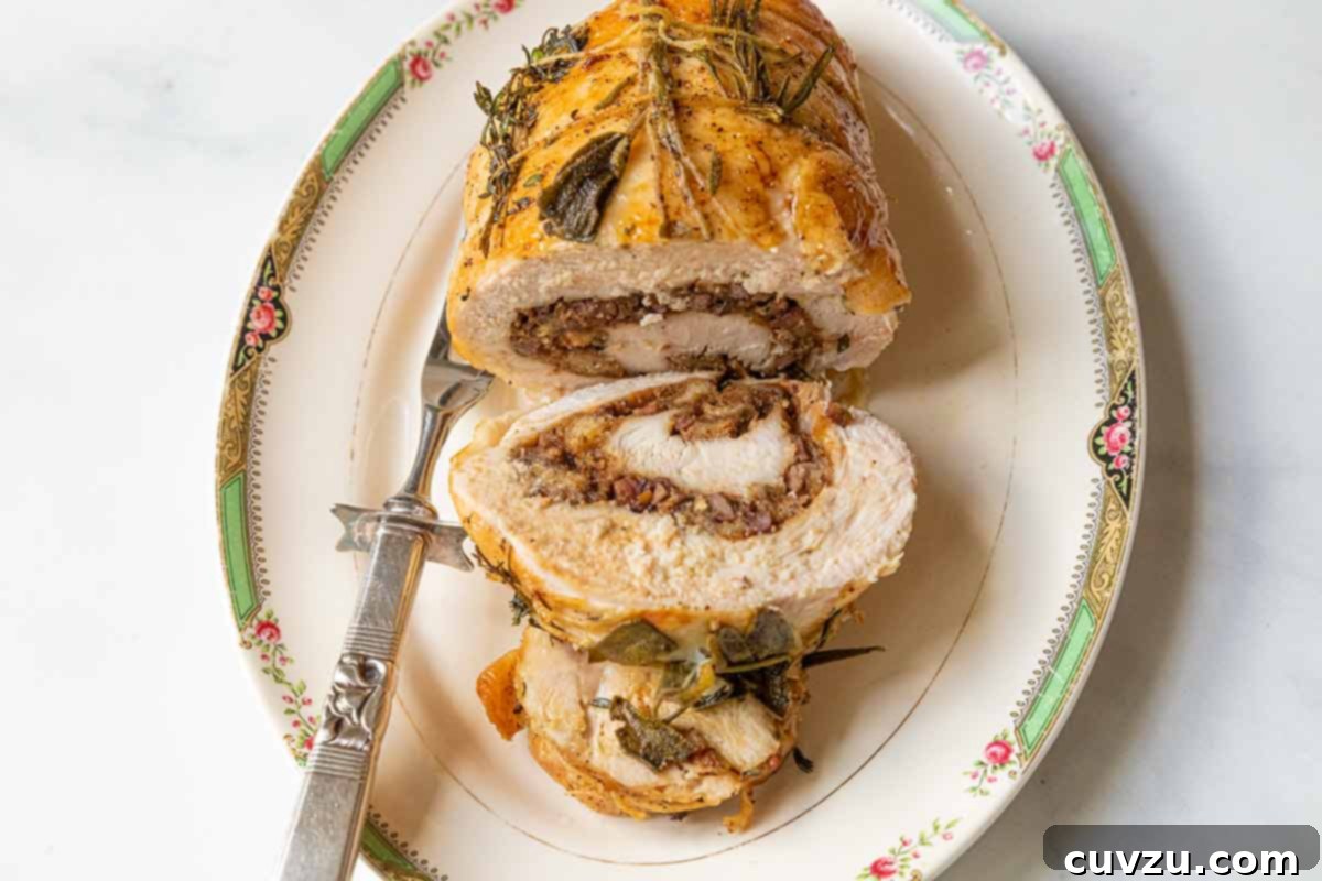 Gourmet Pancetta and Herb Stuffed Turkey Breast 4 A partially sliced pancetta and herb stuffed turkey breast on a serving platter with a serving fork on the side.