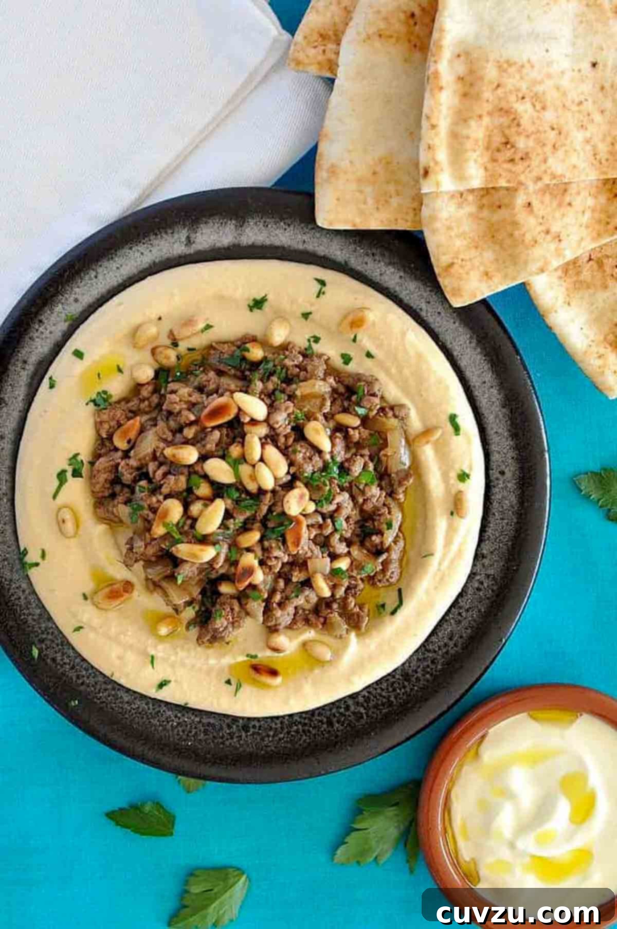 a bowl of Ottolenghi's hummus with lamb on a blue background