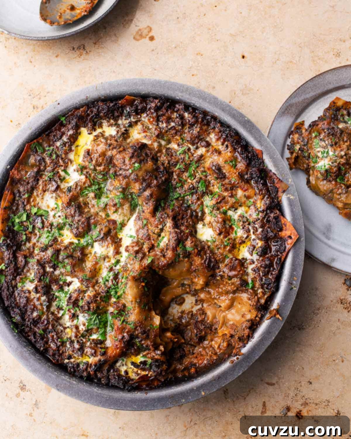 A round dish filled with spicy mushroom lasagna and a serving on a plate beside it.