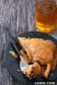 Honey-Drenched Greek Baklava 3 Smaller version of a triangular piece of Greek baklava with honey on a black plate, used as a recipe card image.