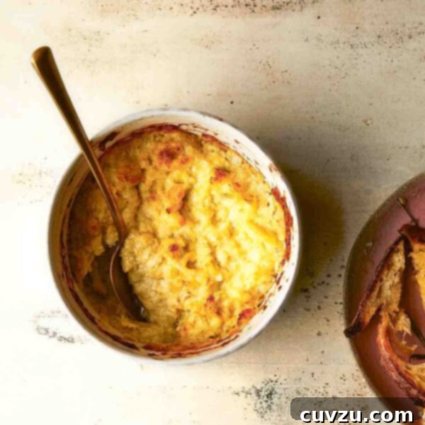 Creamy Baked Artichoke Dip 5 Hot artichoke dip in a white pottery bowl with a serving spoon, beside a bowl of toasted bread.
