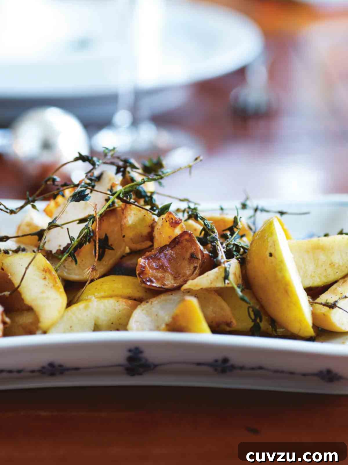A white platter filled with turnip and apples segments, topped with thyme sprigs.