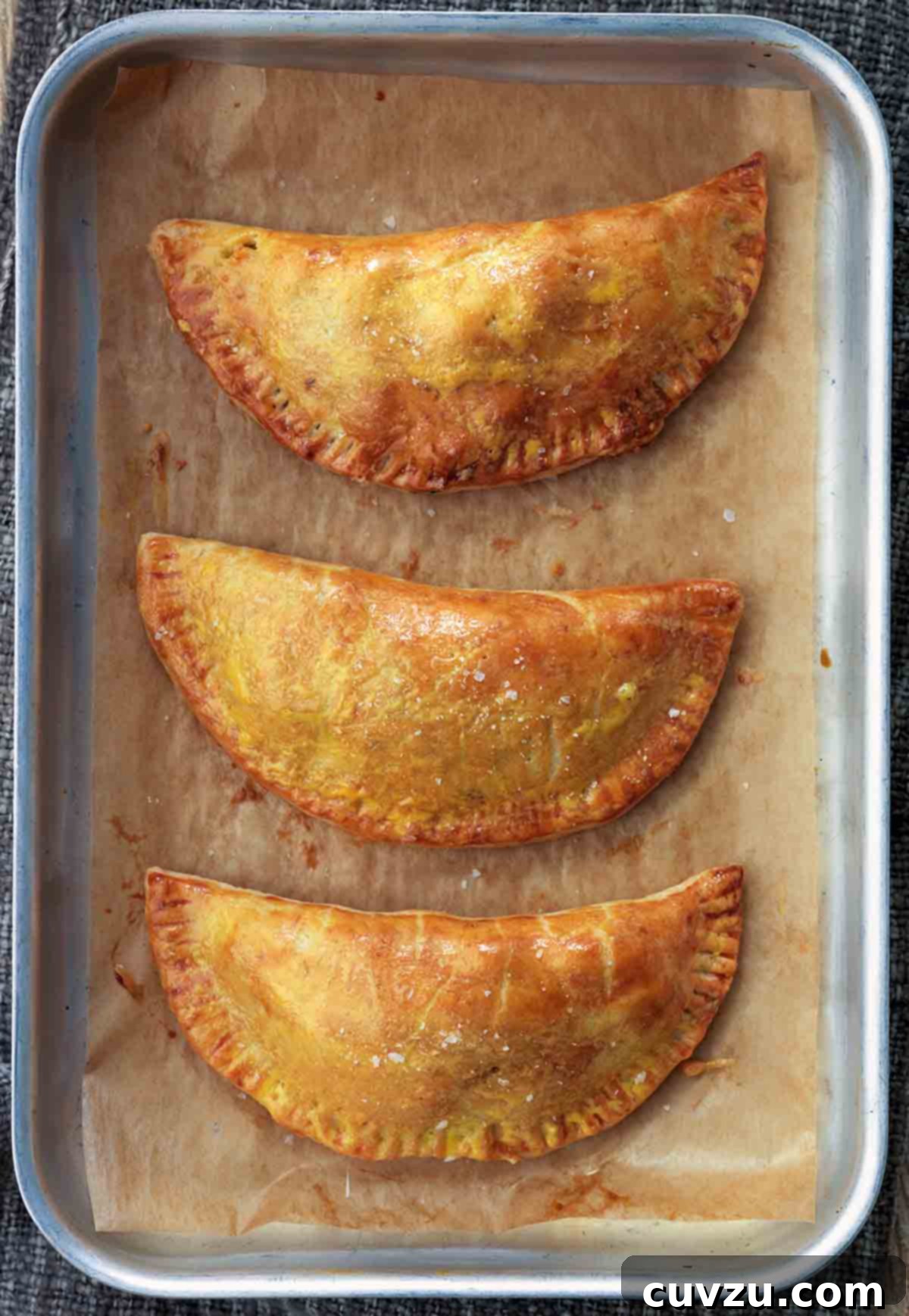 Beyond the Sandwich: 9 Epic Thanksgiving Leftover Ideas 5 Three leftovers turnovers on a parchment-lined small rimmed baking sheet.