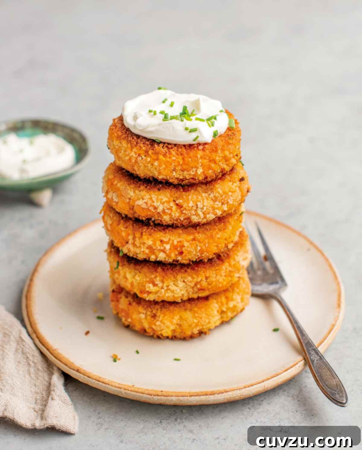 Beyond the Sandwich: 9 Epic Thanksgiving Leftover Ideas 7 Five sweet potato patties stacked on a plate with a dollop of crème fraîche on top and a fork on the side.