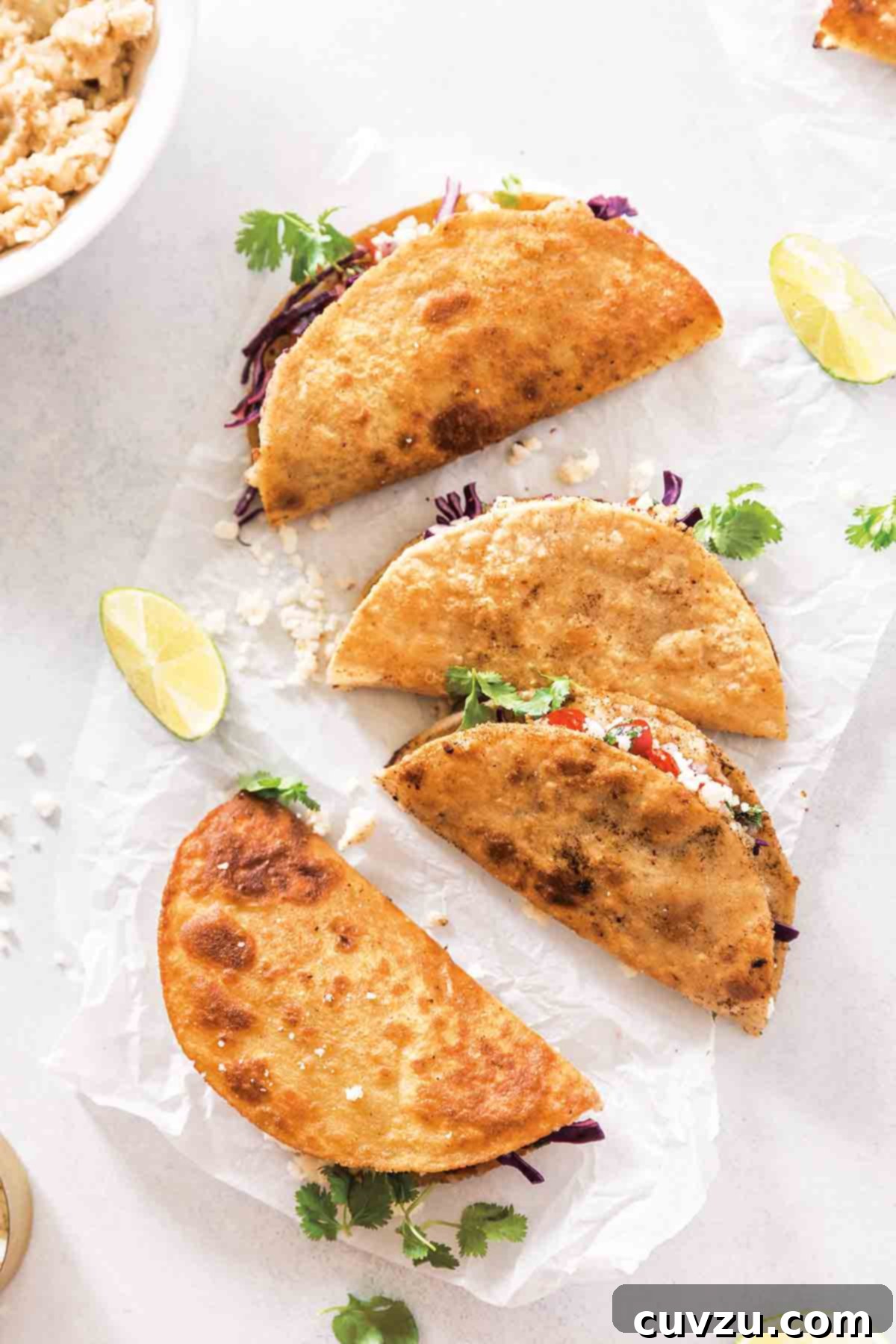 Beyond the Sandwich: 9 Epic Thanksgiving Leftover Ideas 9 Four crispy mashed potato tacos on a sheet of white paper with a couple lime wedges on the side.