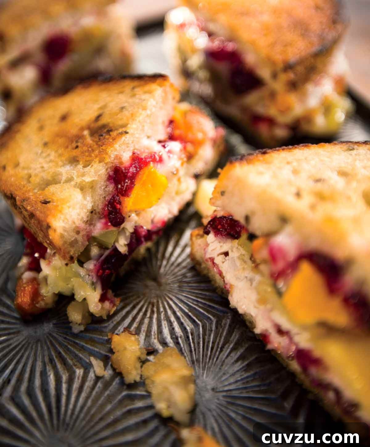 Beyond the Sandwich: 9 Epic Thanksgiving Leftover Ideas 10 Two hot turkey sandwiches, sliced in half on a tray with pieces of cranberry, avocado, and stuffing lying beside them.