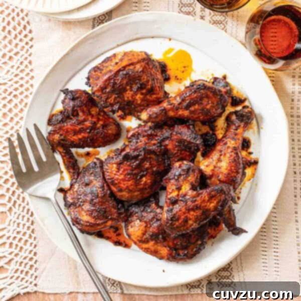 Close-up of garlic, chile, and cumin roast chicken on a white platter with a serving fork.