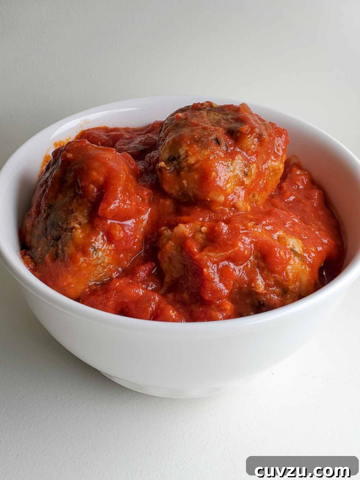 Classic Italian Meatballs 5 A white bowl filled with Italian-style meatballs and tomato sauce.