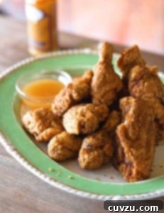 Northern fried chicken piled on a green plate, with a bowl of gravy alongside.