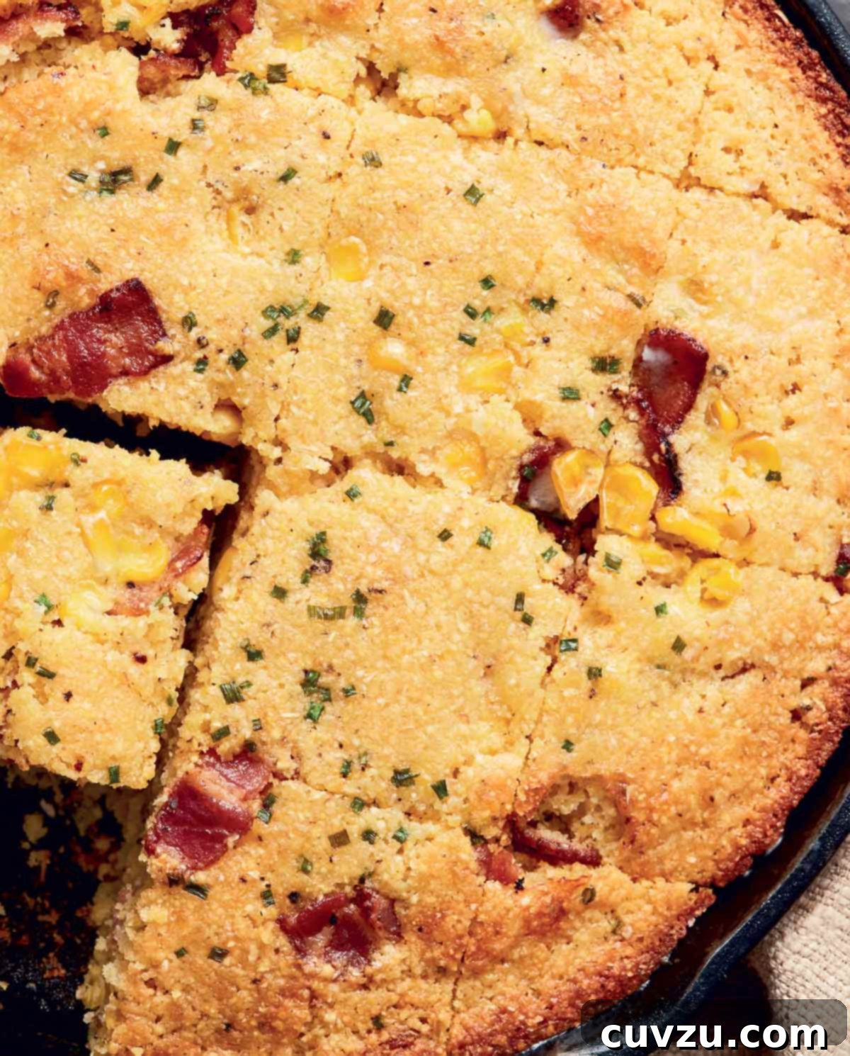 Dorie Greenspan's quick cornbread, featuring savory bacon, sweet corn, and vibrant green onions, baked to golden perfection in a rustic cast-iron skillet and cut into inviting squares.