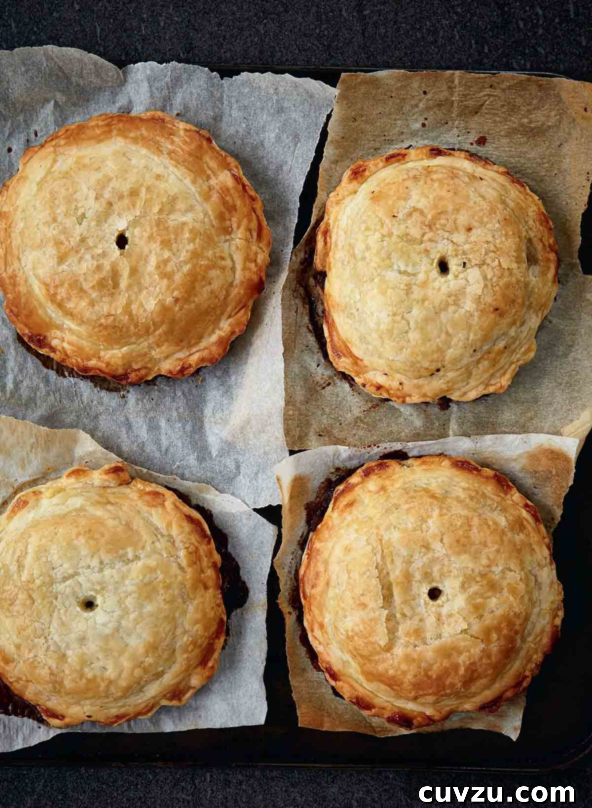 Four individual mushroom wellingtons with spinach and walnuts on a squares of parchment paper.