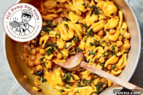 Orecchiette with chickpeas, turmeric, and greens in a large pot with a wooden spoon, on a countertop.