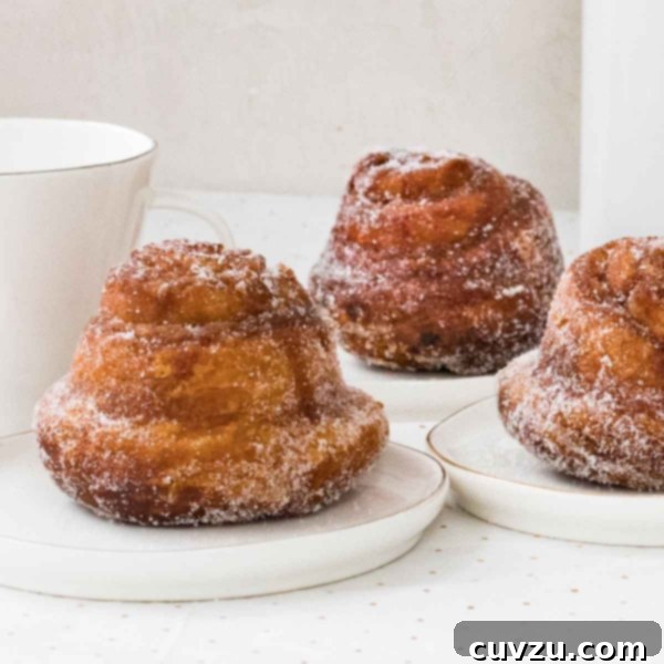 Golden Breakfast Spirals 5 A square image of three beautifully golden and sugar-dusted fresh morning buns on individual white plates.