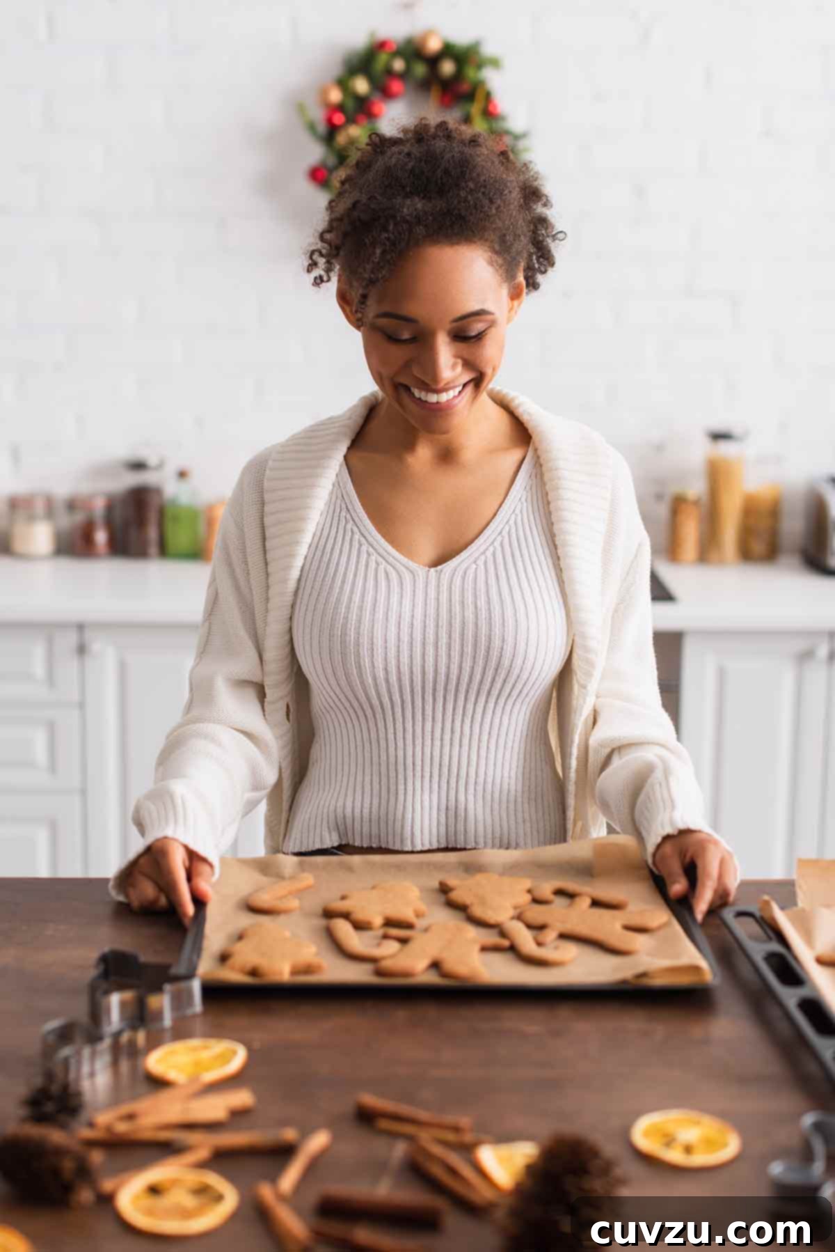 Host the Ultimate Cookie Swap 7 A woman holding a baking tray of gingerbread cookies