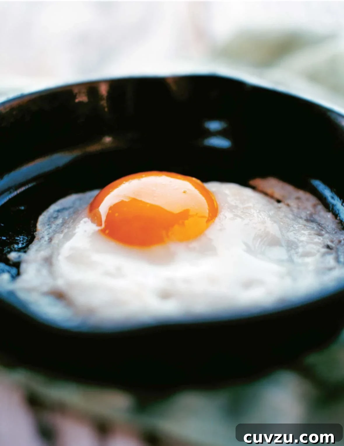 The Secret to Perfectly Fried Eggs 2 A perfectly fried egg, sunny side up, resting in a small black skillet, ready to be served.