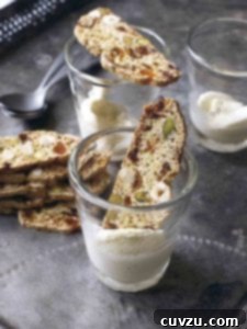 Mediterranean Medley Biscotti 3 Fig, apricot, and pistachio biscotti resting inside or on top of two glasses and a stack of biscotti beside the glassware.