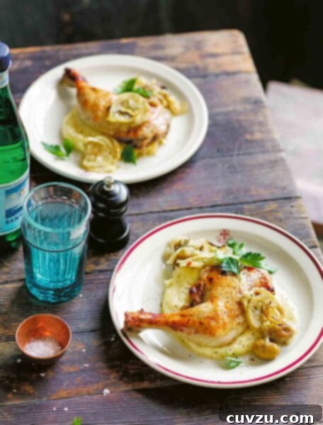 A plate with a leg and thigh of Mediterranean chicken with fennel and green olives sitting on a bed of mashed potatoes.