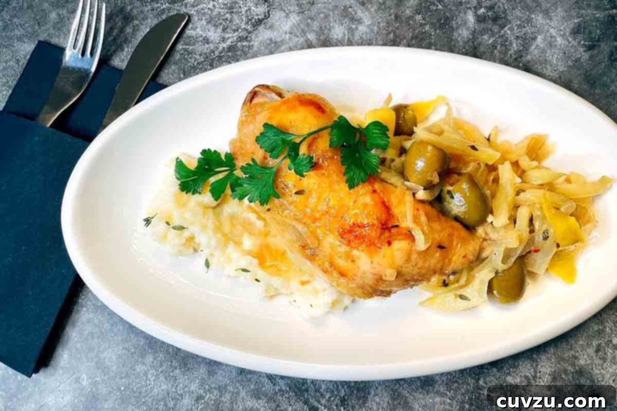 Fennel and Green Olive Mediterranean Chicken 5 A plate with a leg and thigh of Mediterranean chicken with fennel and green olives sitting on a bed of mashed potatoes, garnished with fresh parsley.