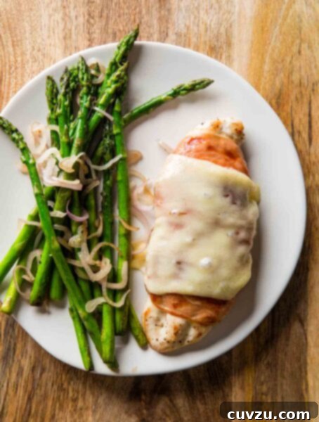 Crisp Prosciutto-Wrapped Chicken with Tender Asparagus 3 A white plate with prosciutto-wrapped chicken with asparagus on the side