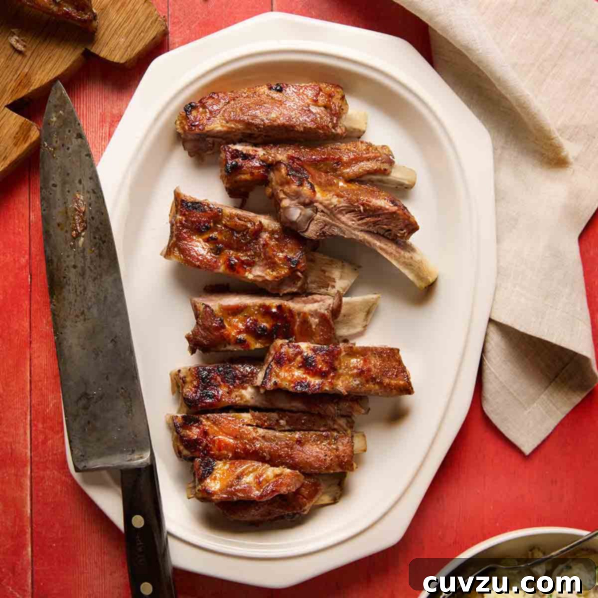 A platter of pressure cooker ribs cut into individual ribs, with a carving knife on the side.