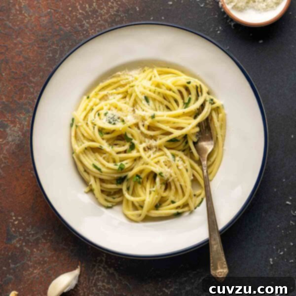 A plate filled with pasta with butter and Parmesan, garnished with parsley.