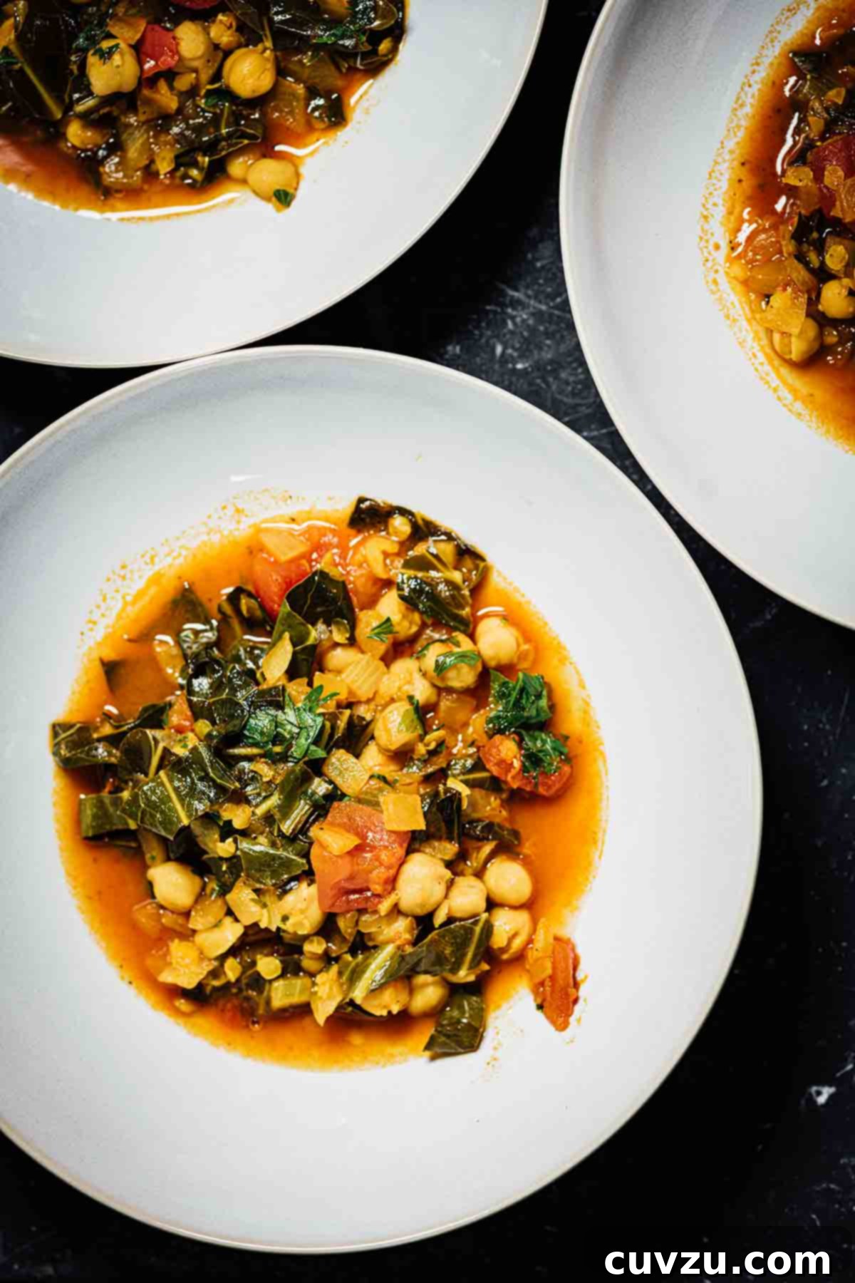 Three white bowls filled with a hearty collard greens, chickpea, and lentil soup.