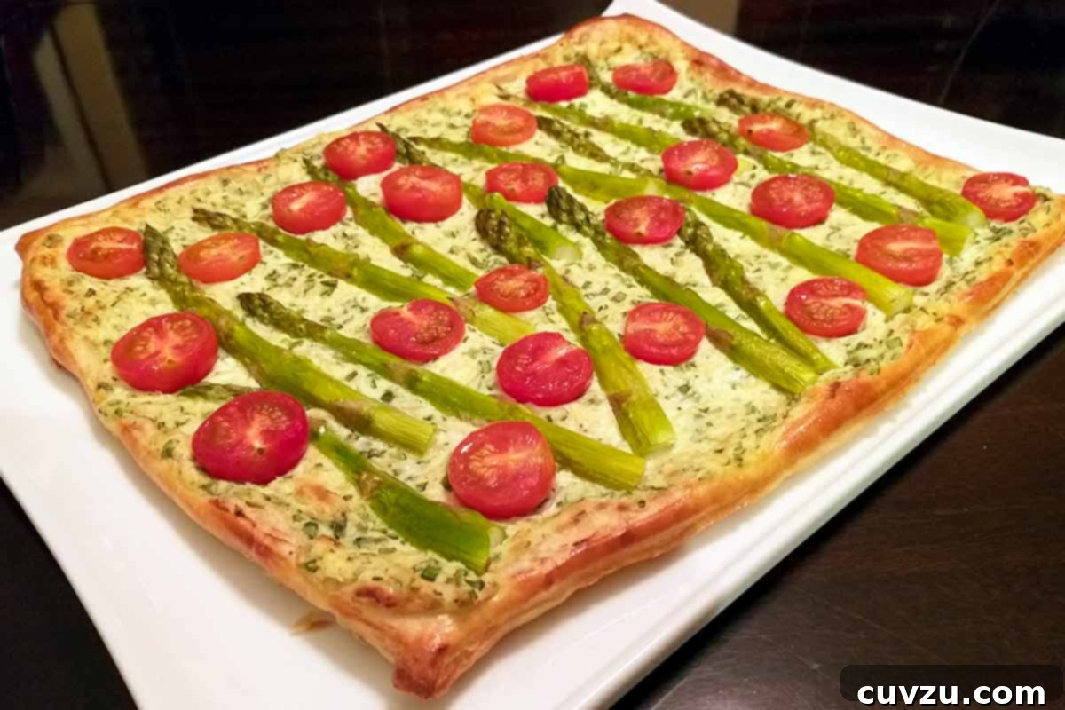A cherry tomato, asparagus, and herbed ricotta tart on a white serving platter.