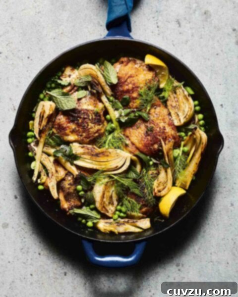 A cast-iron skillet filled with chicken thighs, peas, and fennel.