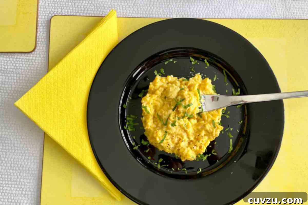 Julia Child's Simple Scrambled Eggs for Young Chefs 5 A black plate topped with easy scrambled eggs on a yellow placemat with a yellow napkin on the side