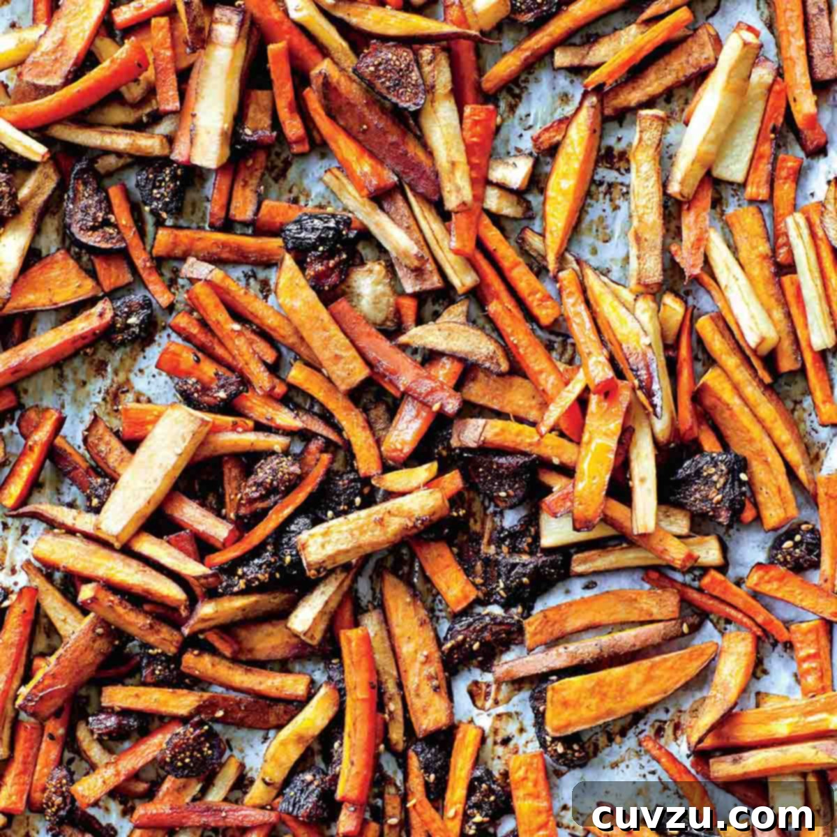 Roasted tzimmes, a vibrant and sweet carrot dish, spread on a large sheet pan, ready for the Passover table.