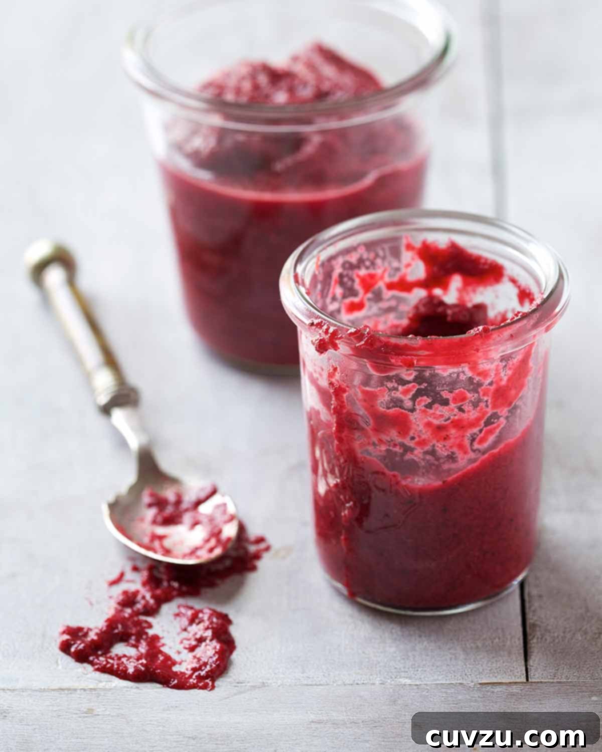Two clear glass jars filled with vibrant homemade chrain, with a silver spoon resting beside them.
