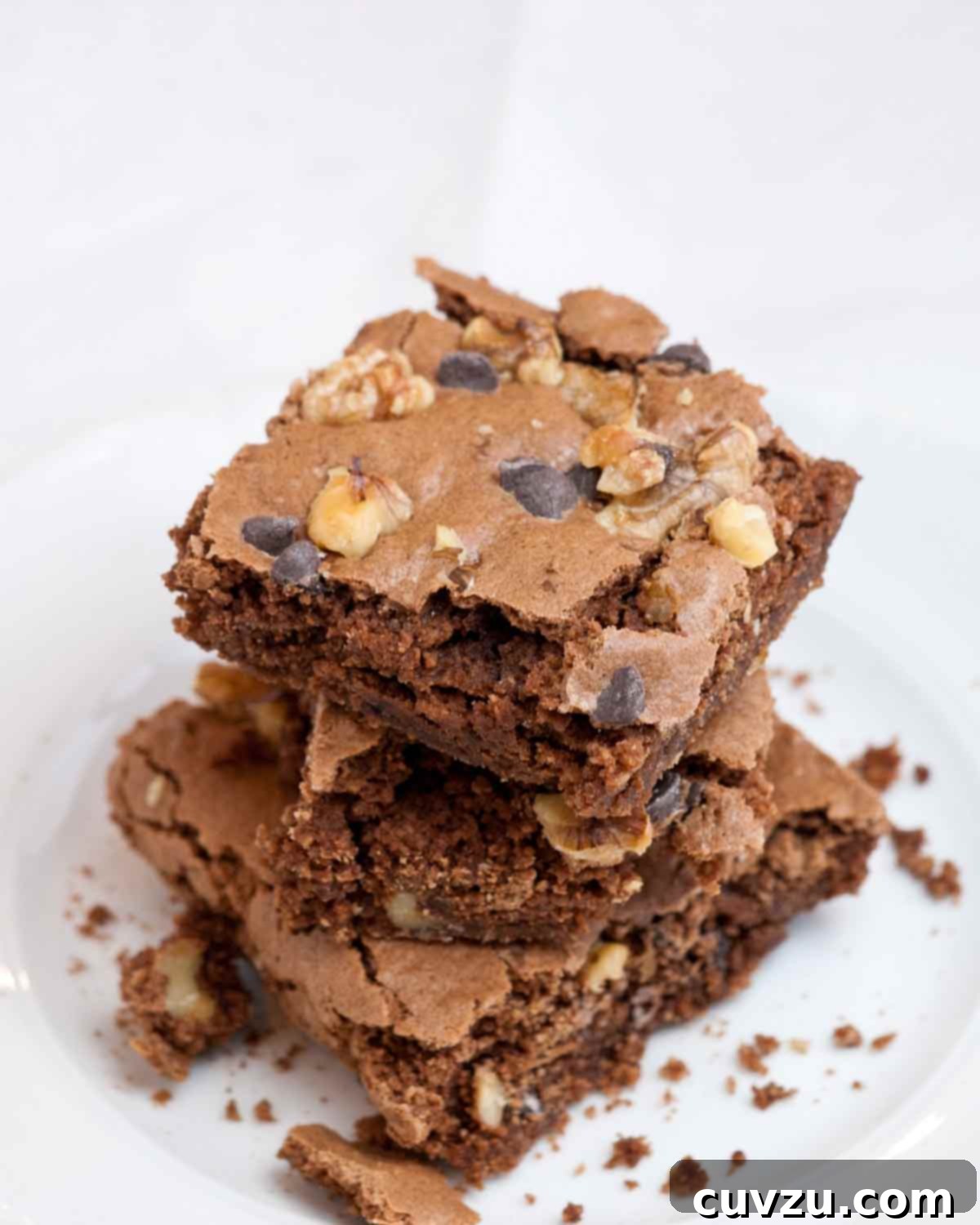 Three perfectly stacked Passover brownies on a white plate, showcasing their fudgy texture.