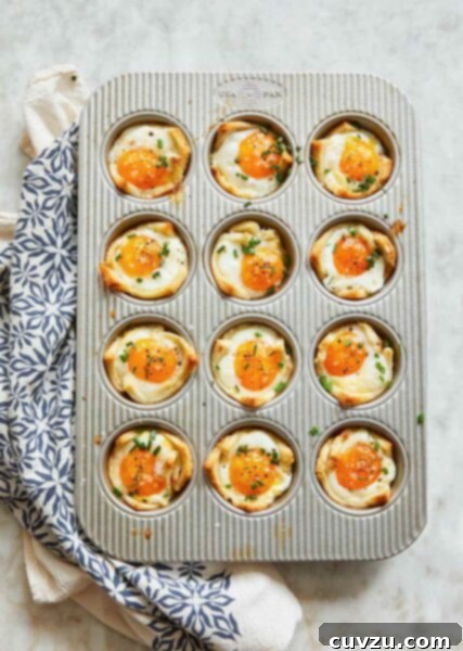 A muffin tin filled with 12 baked egg and toast cups