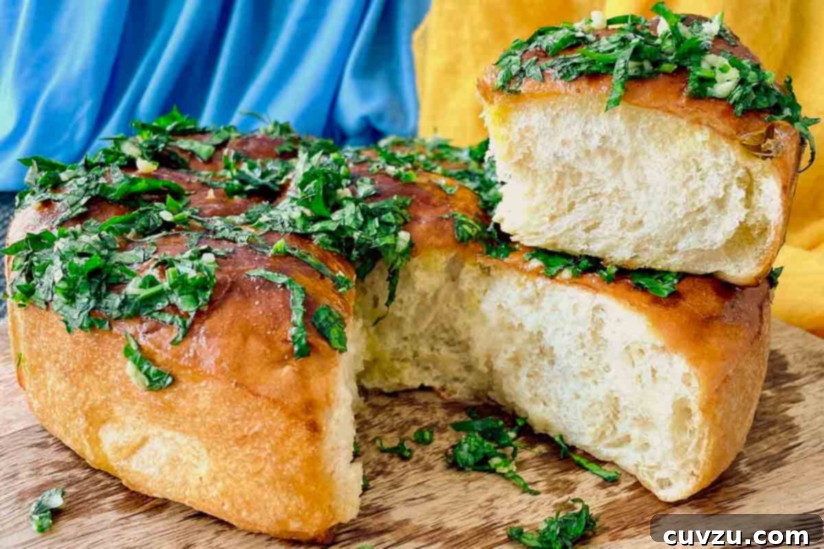 Pampushky Ukrainian Garlic Bread 9 A piece of Ukrainian garlic bread pulled apart from the whole loaf, topped with parsley and garlic, ready to be savored.