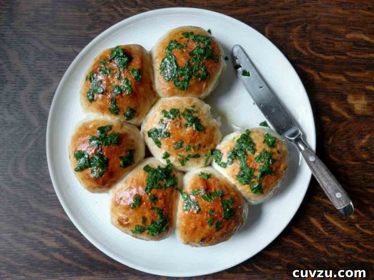 Pampushky Ukrainian Garlic Bread 7 Seven Ukrainian garlic bread rolls on a white plate with a knife on the side, highlighting their rustic charm and readiness for enjoyment.