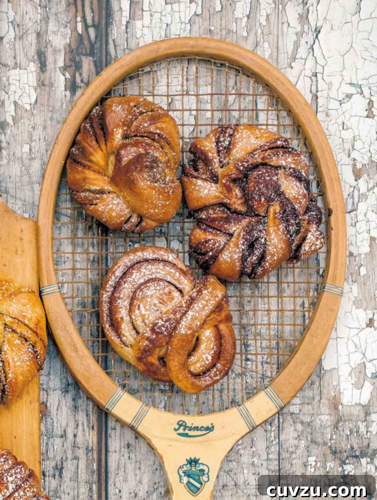 Fika's Cardamom Swirls 3 Three perfectly baked Swedish fika buns, each with a different filling and glaze, artfully arranged on an antique tennis racket.