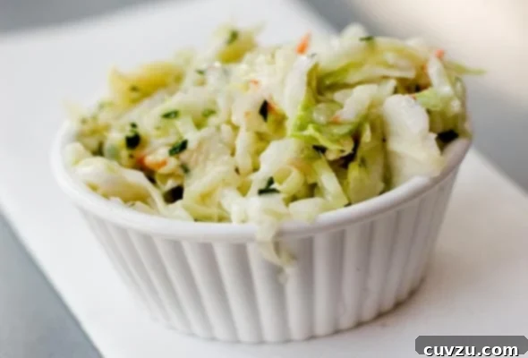 Maple-Kissed Slaw 2 A small white ramekin generously filled with vibrant, creamy coleslaw featuring a hint of maple syrup