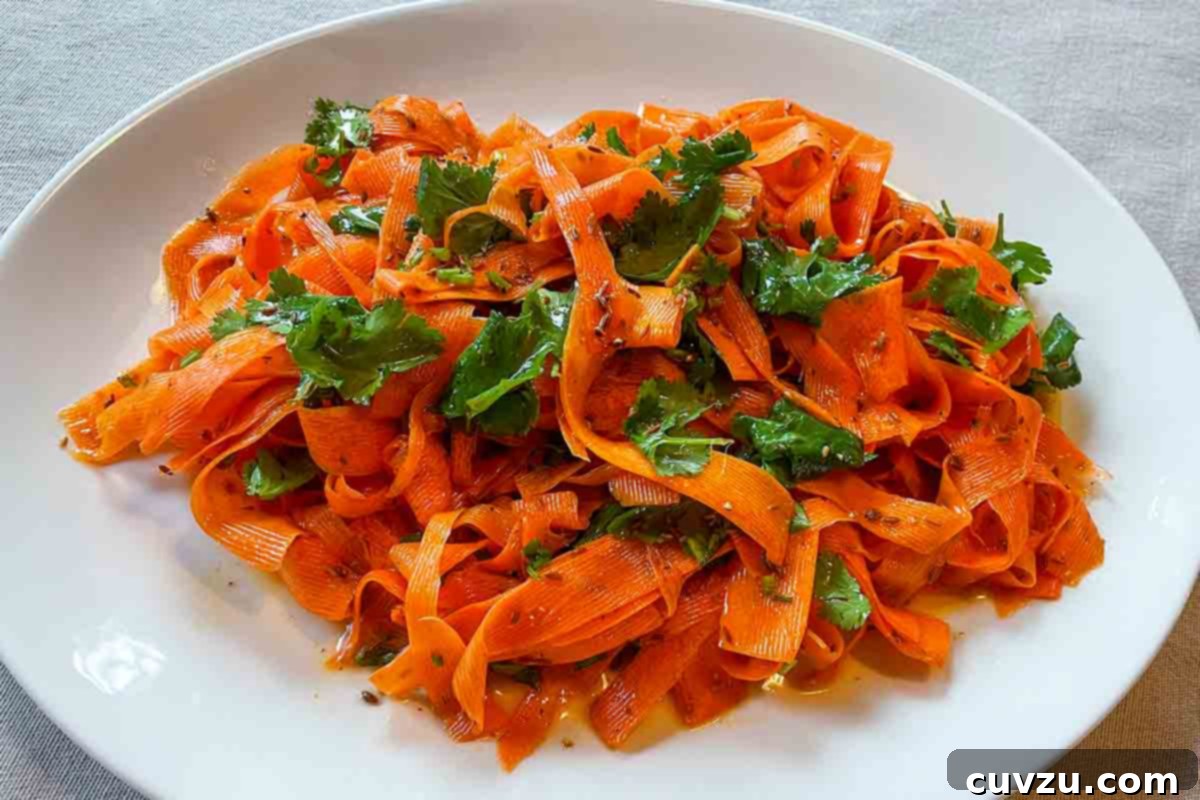 Vibrant Shaved Carrot Salad 5 A white round platter filled with carrot ribbon salad, generously topped with cilantro, showcasing its fresh appeal.
