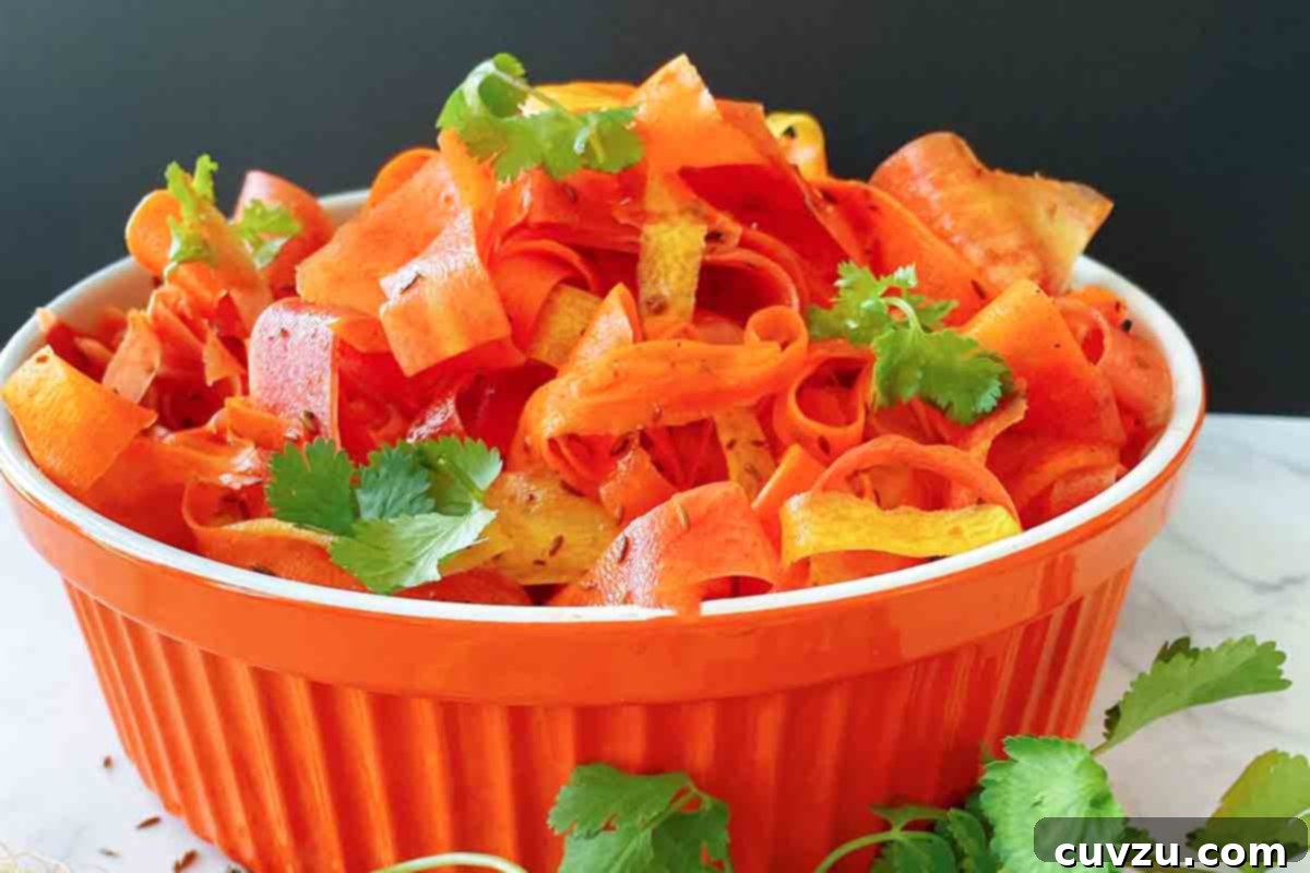 Vibrant Shaved Carrot Salad 7 An orange serving bowl filled with carrot ribbon salad, beautifully garnished with cilantro leaves.